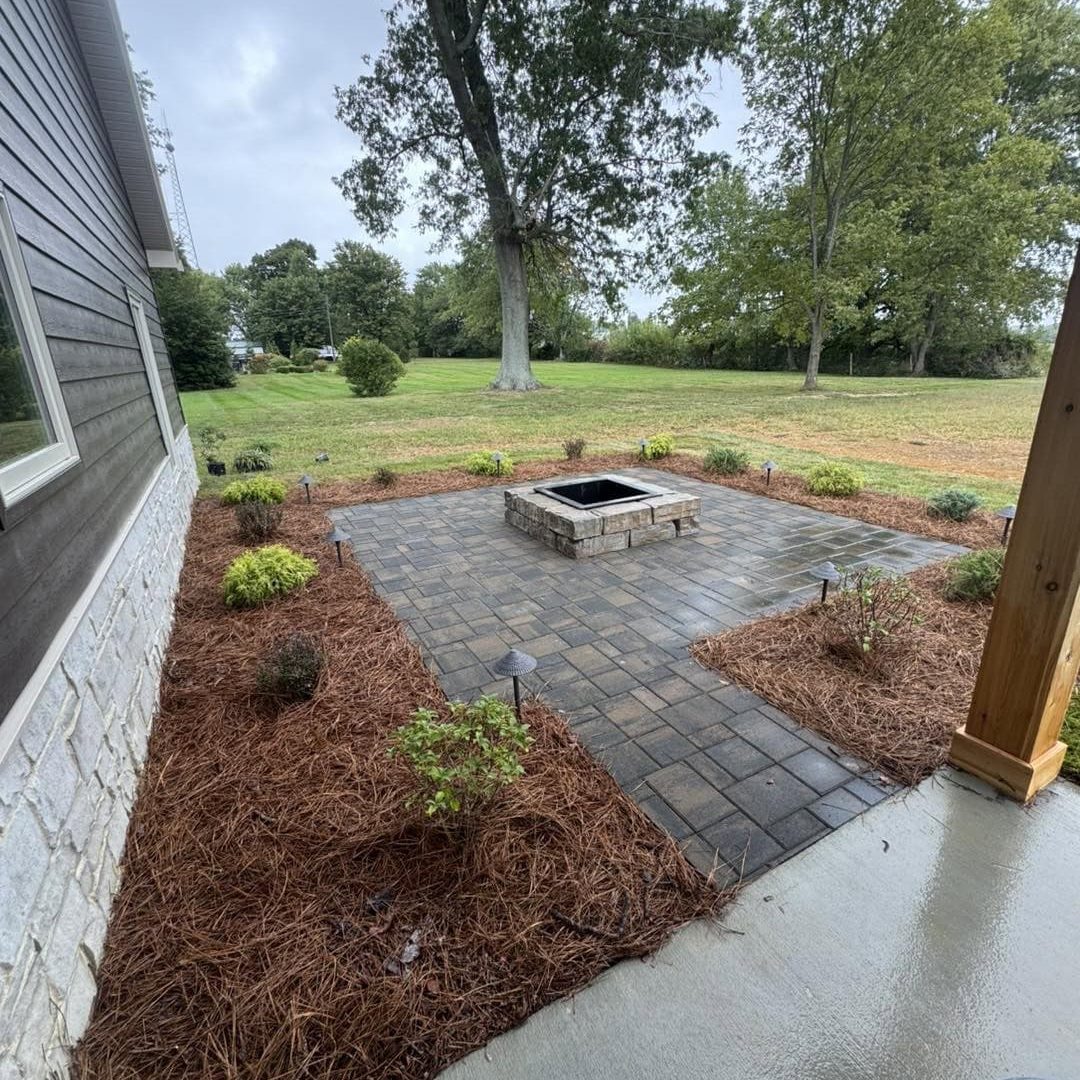 Beautiful backyard fire pit with paver patio and surrounding garden beds for outdoor gatherings.
